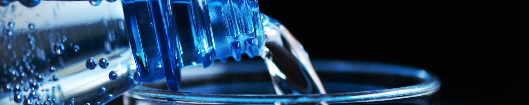 up close of bottle of water pouring into a glass